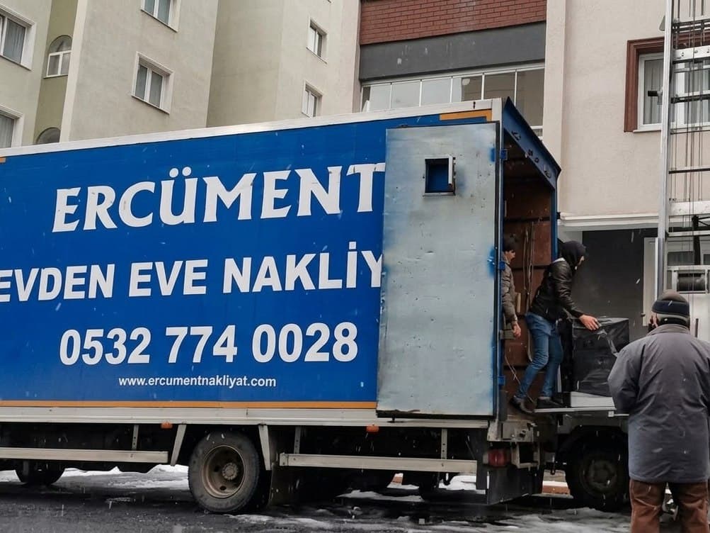 Karlı bir günde Ercüment Nakliyat ekibi eşyaları kamyona yüklüyor, binaya dış cephe asansörü kurulmuş